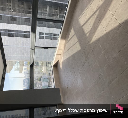 ריצוף אריחי גרניט פורצלן בחלל מרווח לצד חלונות זכוכית גדולים